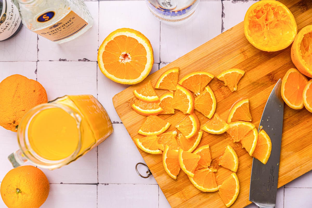 slices of orange cut into quarters on wooden cutting board on counter.