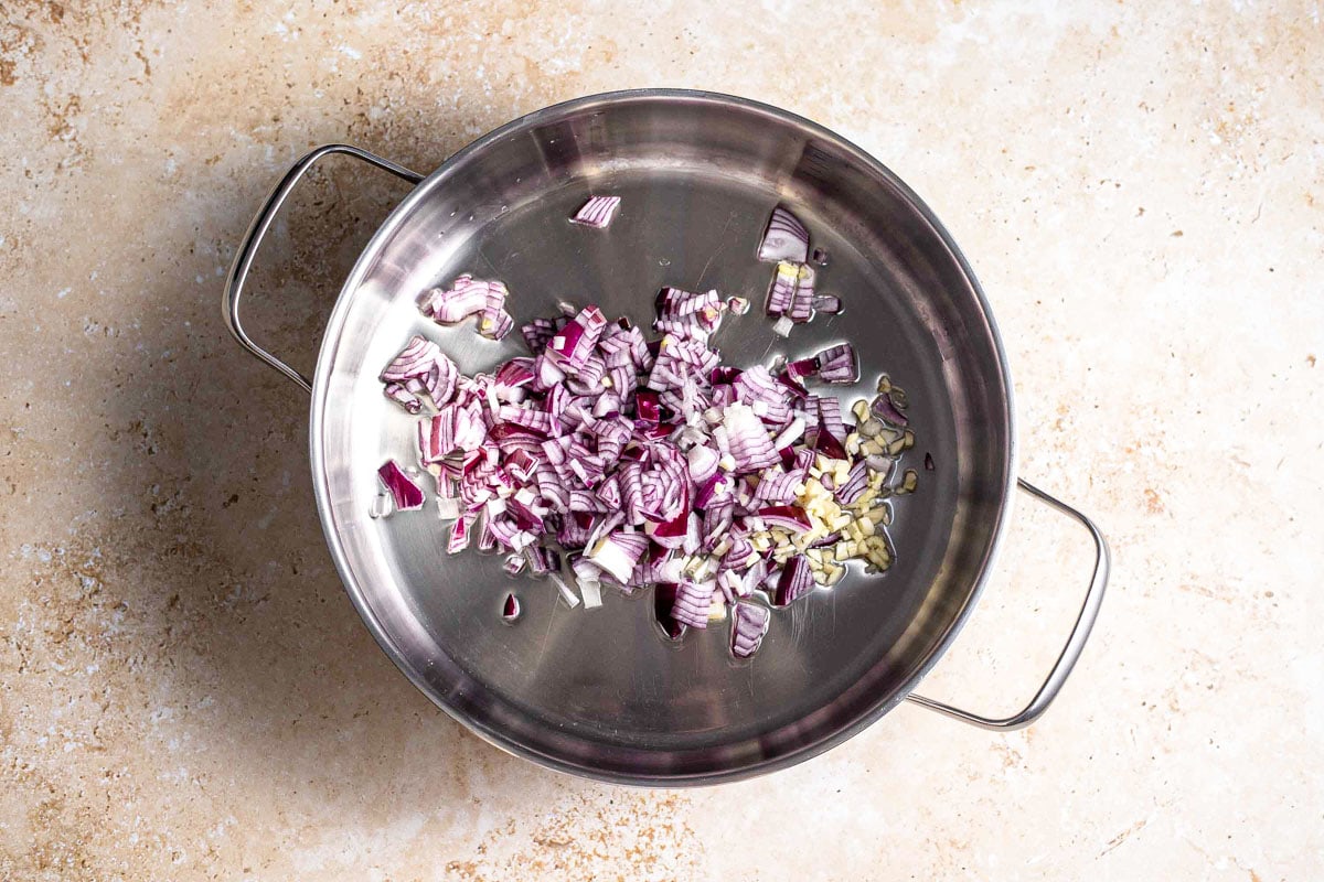 chopped red onions in silver pot on counter top.