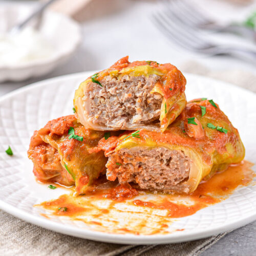 cabbage rolls on white plate cut in half.