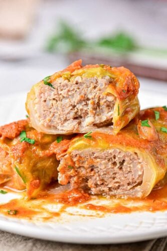 ukrainian cabbage rolls recipe cabbage rolls stacked on plate and cut in half showing meat inside.