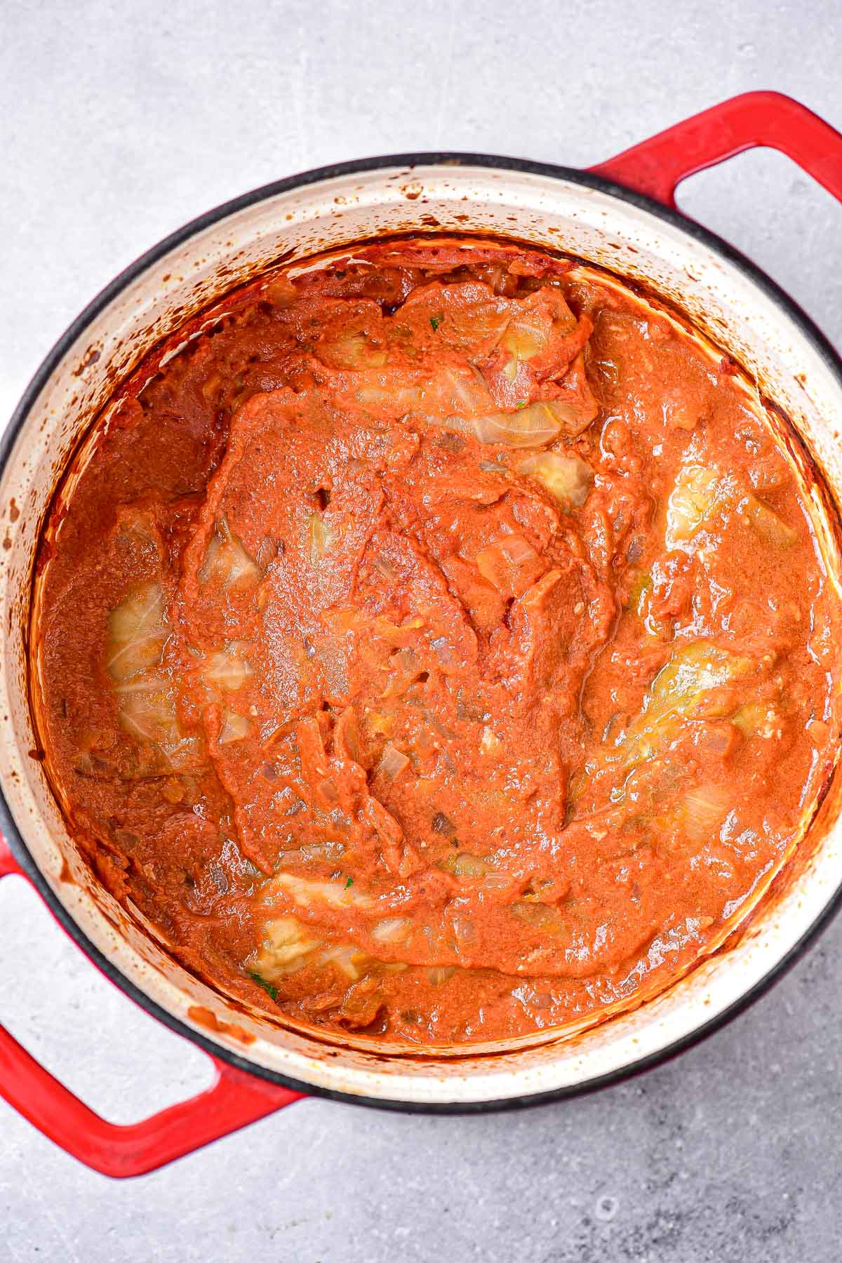 thickened tomato sauce in large pot covering cabbage rolls.