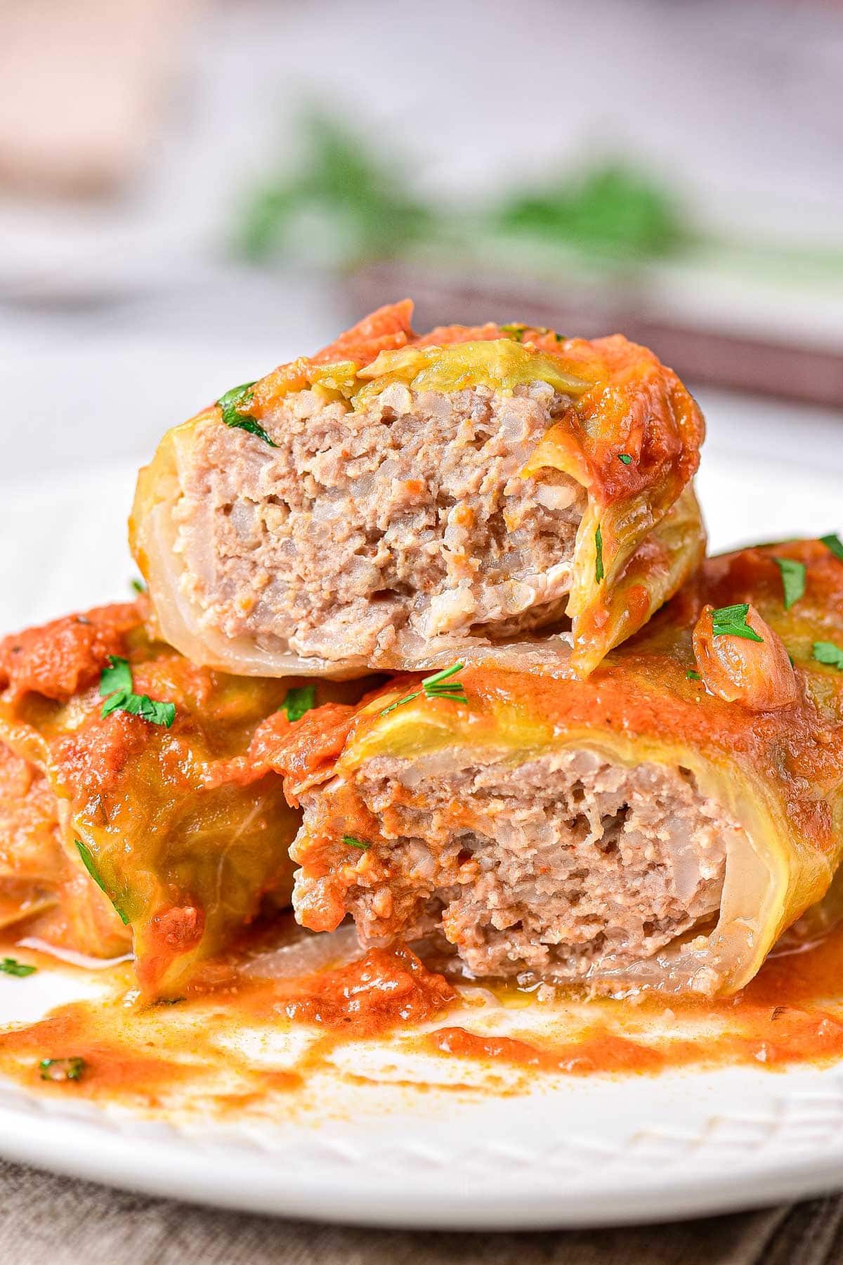 cabbage rolls stacked on plate and cut in half showing meat inside.
