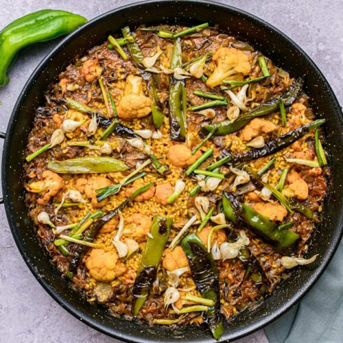 large black pan sitting on counter filled with vegetable paella.