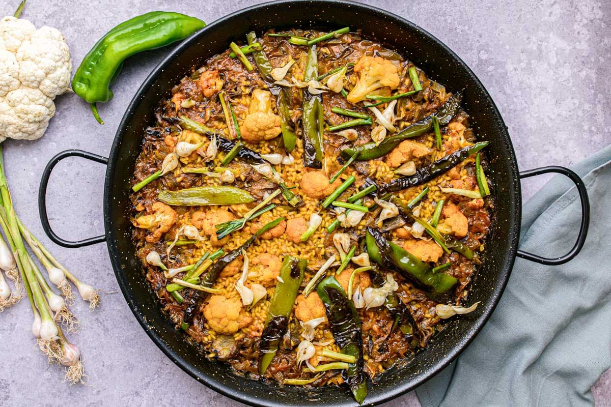large black pan sitting on counter filled with vegetable paella.