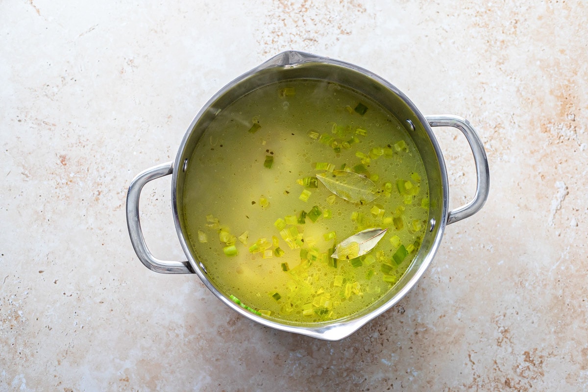 large silver pot filled with yellow broth with counter top around.