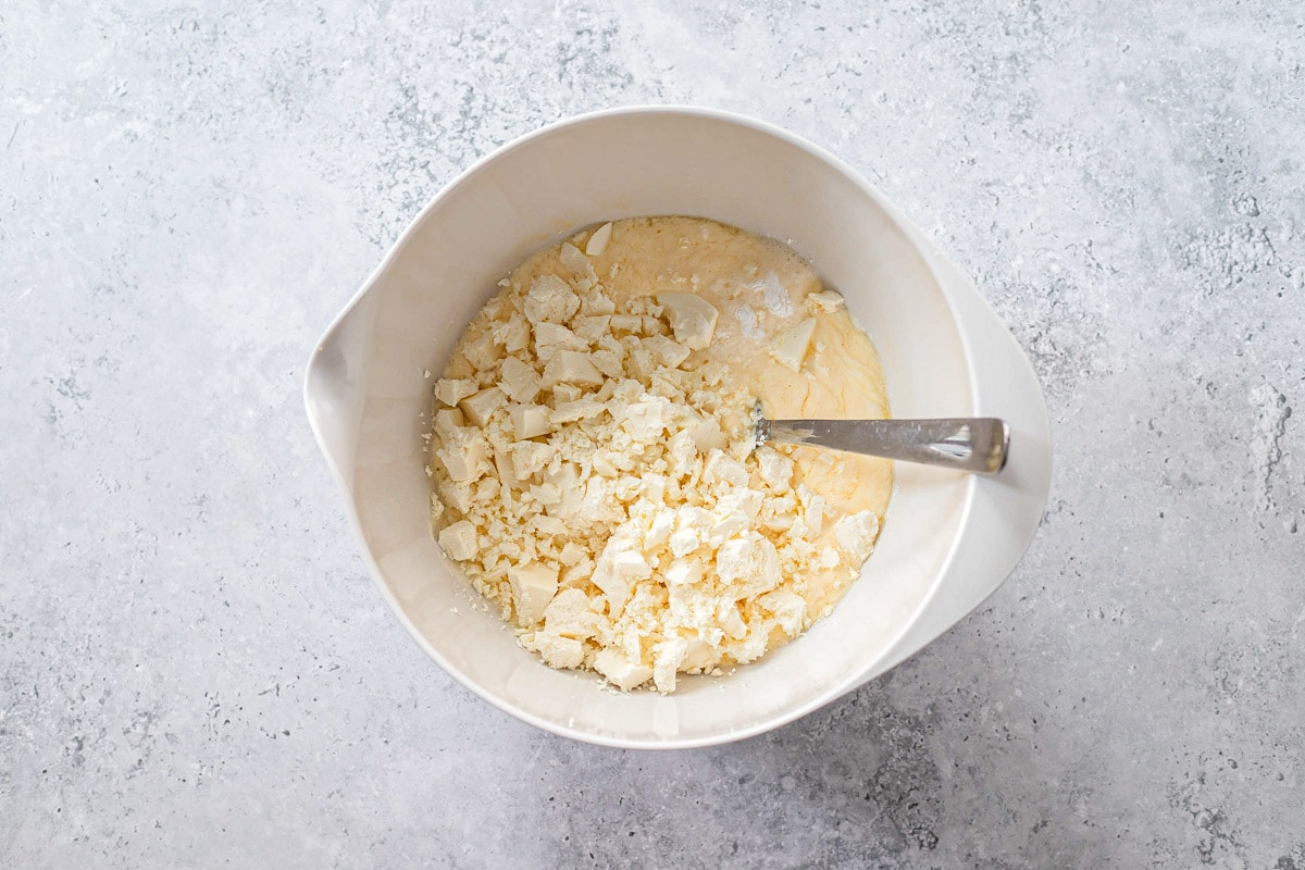 silver spoon sticking out of mixing bowl with feta cheese crumbled inside.