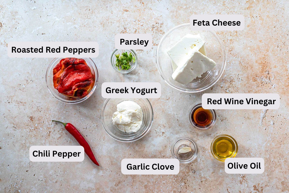 ingredients to make cheesy greek dip on counter in bowls with labels.