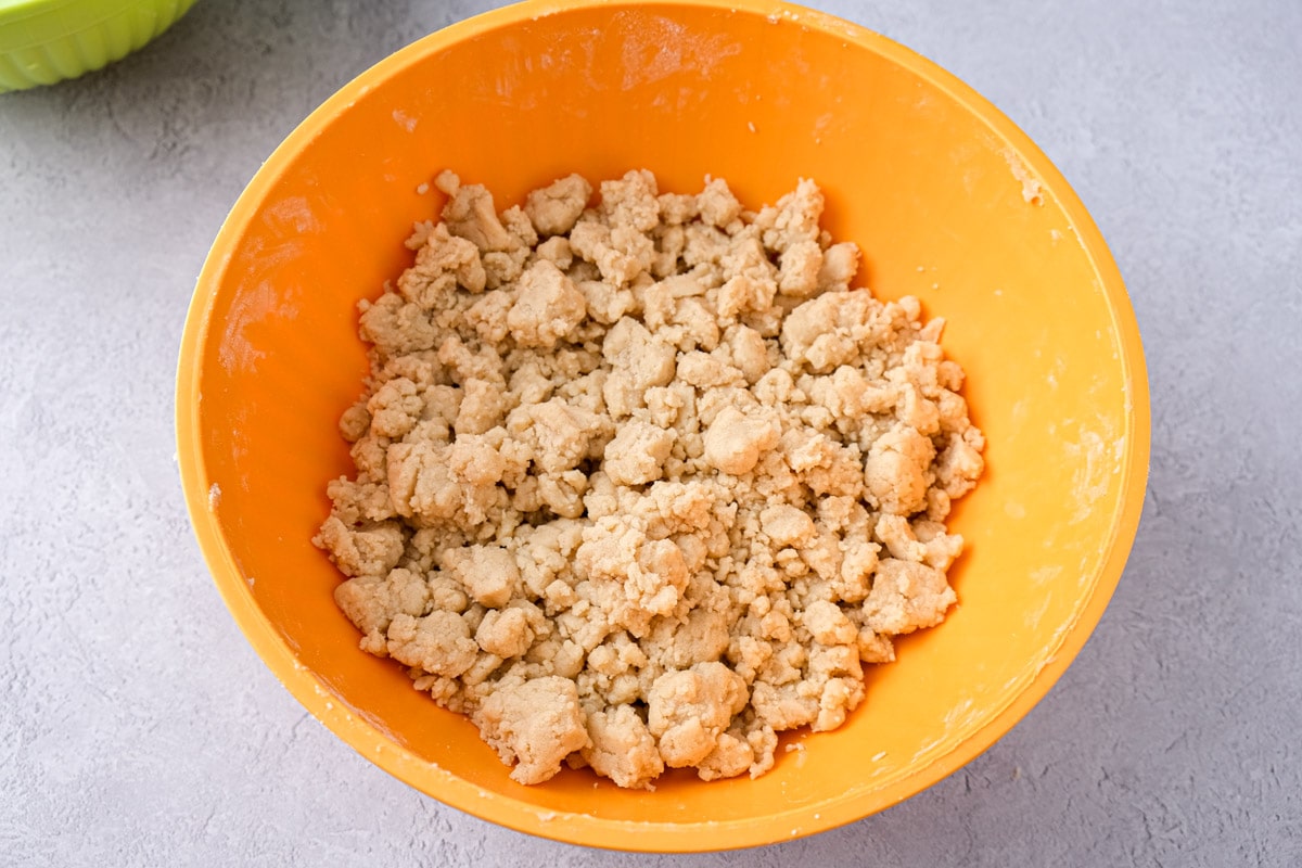 raw streusel buttery crumbs in orange mixing bowl.