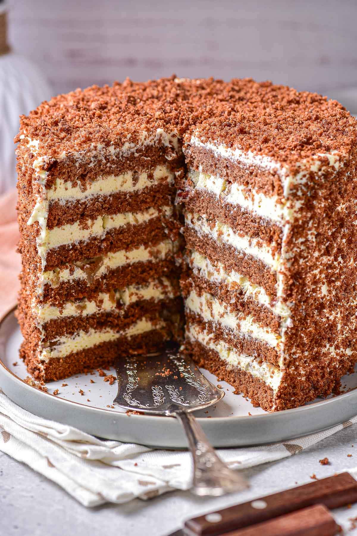 tall honey cake with layers on plate with serving cake lifter in front.