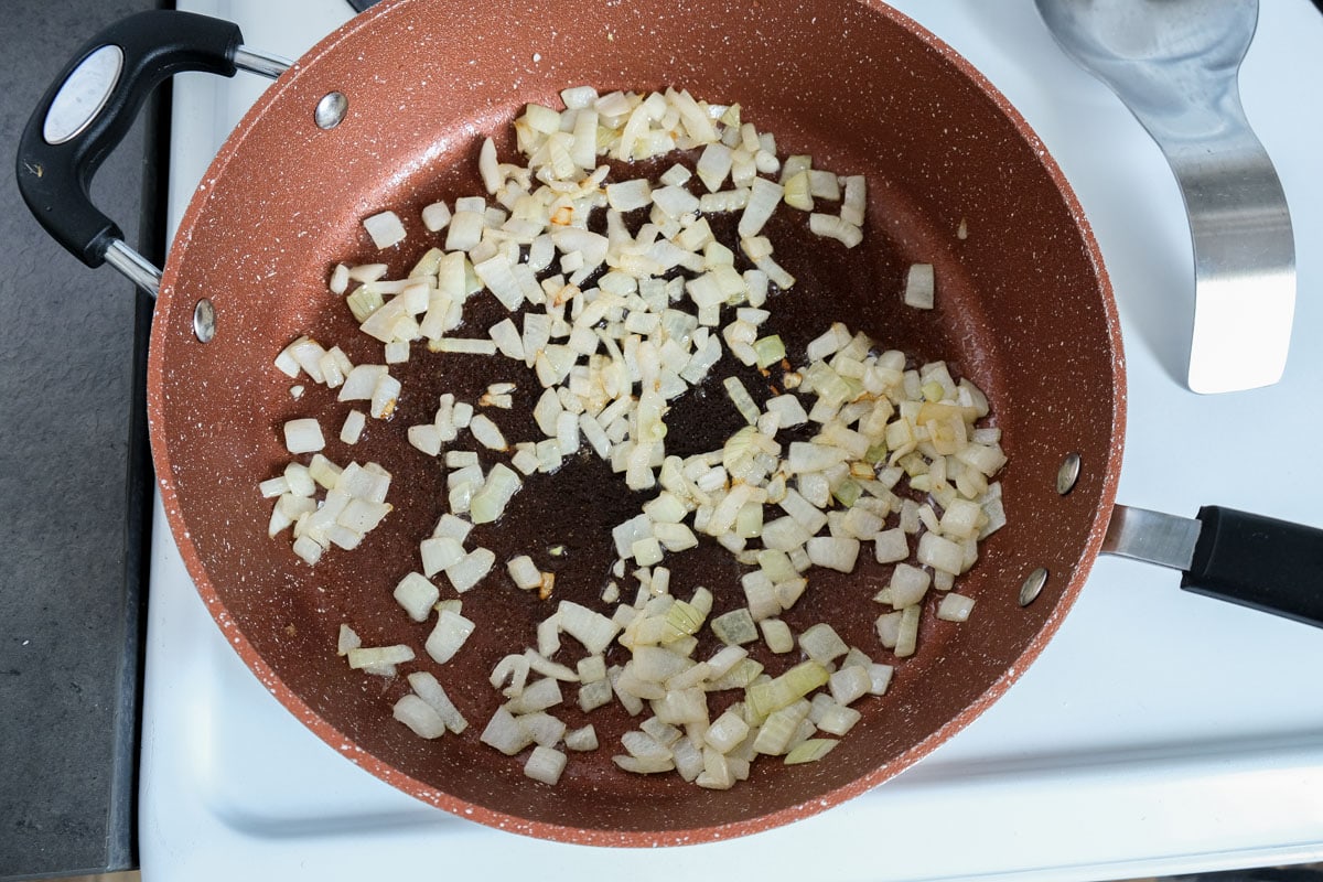 diced onion frying in pan on stove top.