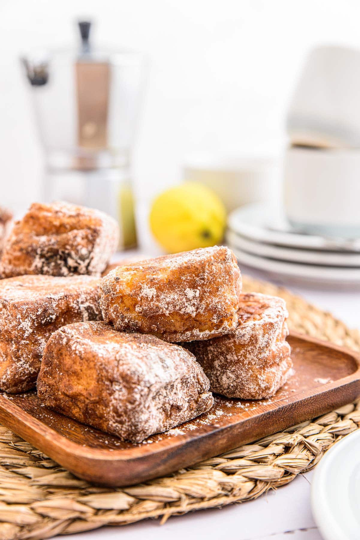 cubes of leche frita coated in cinnamon and sugar in a small stack on platter on counter.