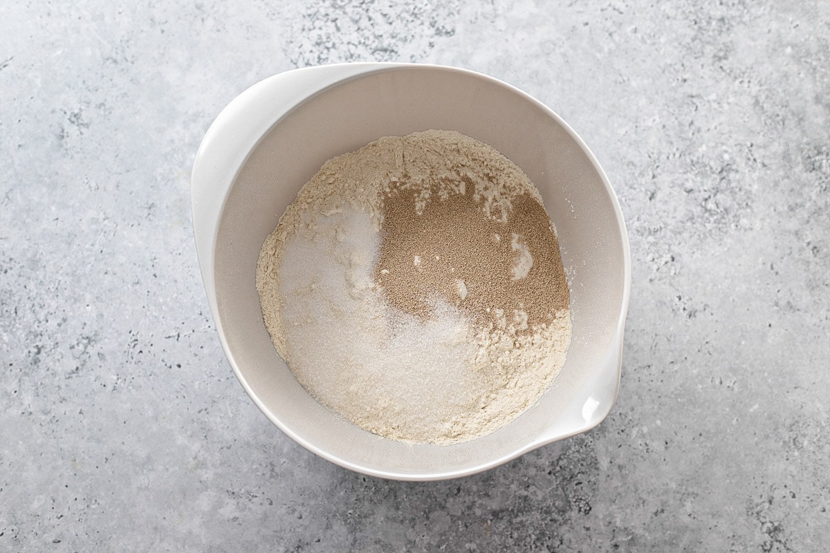 flour and dry yeast in white mixing bowl on counter.
