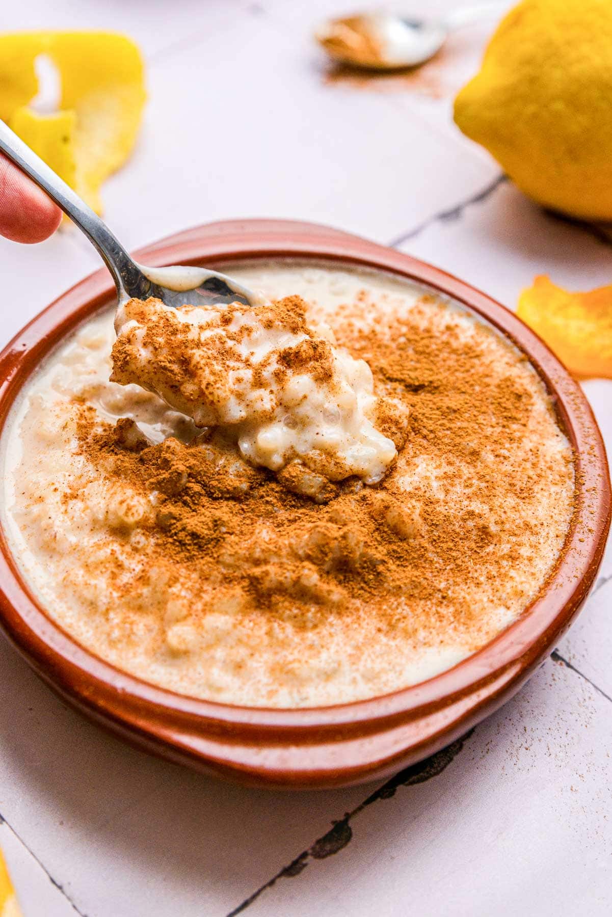 red bowl of rice pudding covered in cinnamon with silver spoon sticking out.