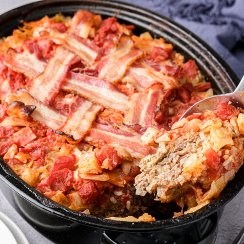 cabbage roll casserole in black roasting pan with spoon removing some.