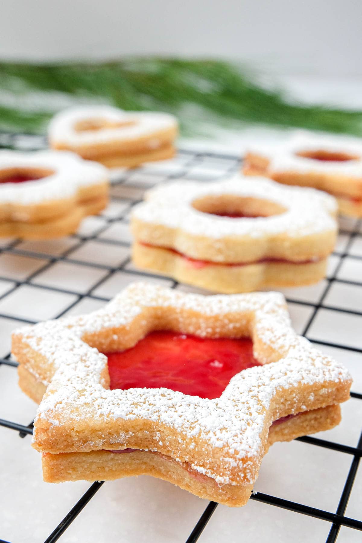 close up shot of star shaped linzer cookie with red jam on cookie rack.