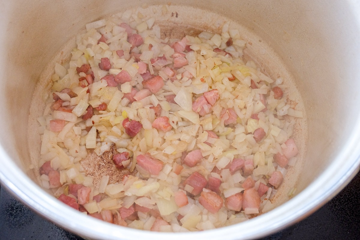 chopped onions and pancetta bacon in bottom of pot on stove.
