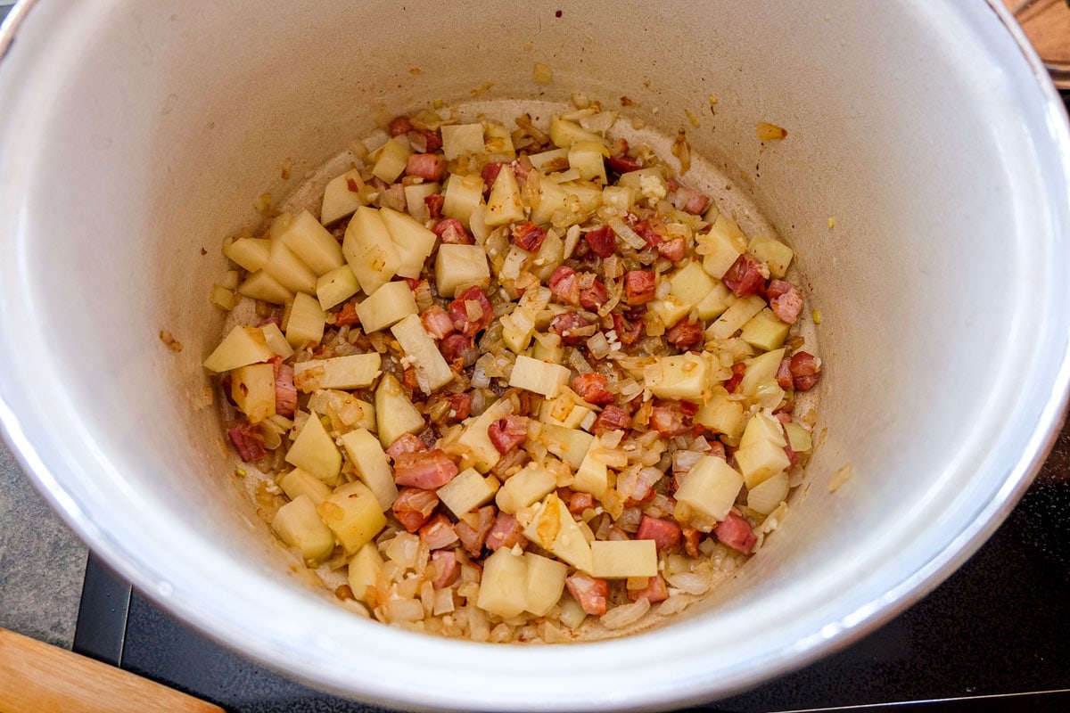 potatoes onions and pancetta in pot on stove.