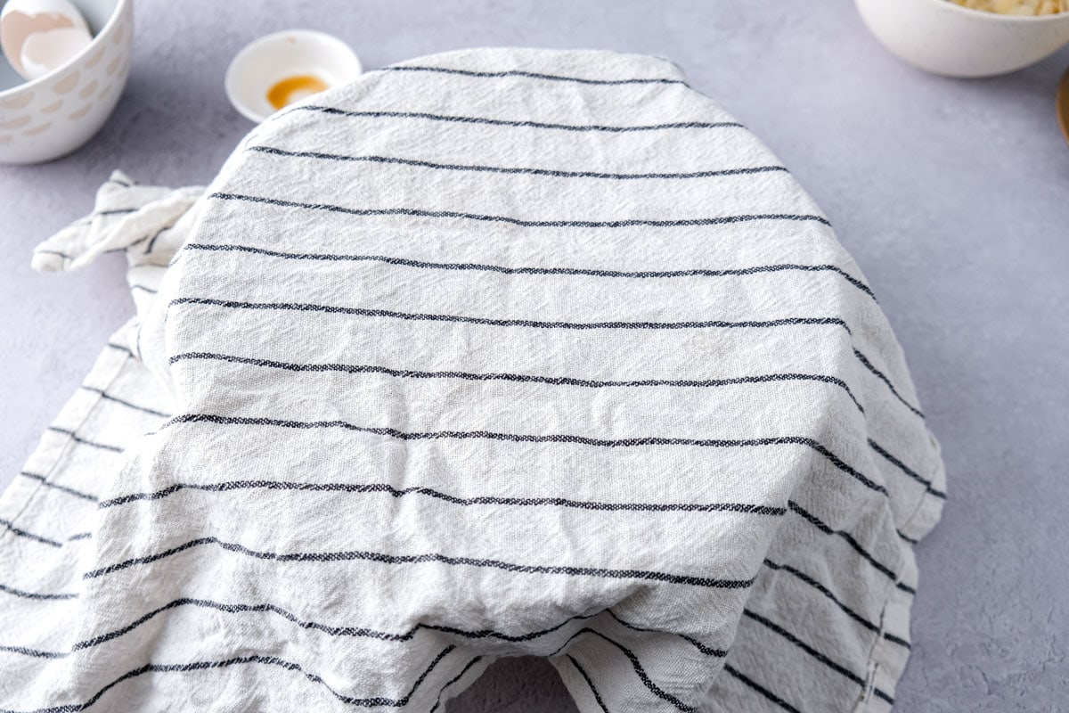 white towel with black stripes covering bowl on counter.