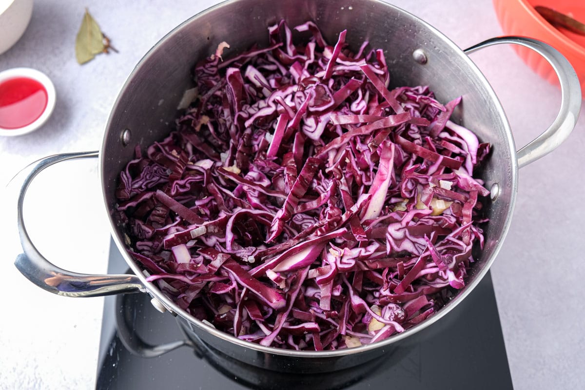 chopped red cabbage in large silver pot on cooking plate.