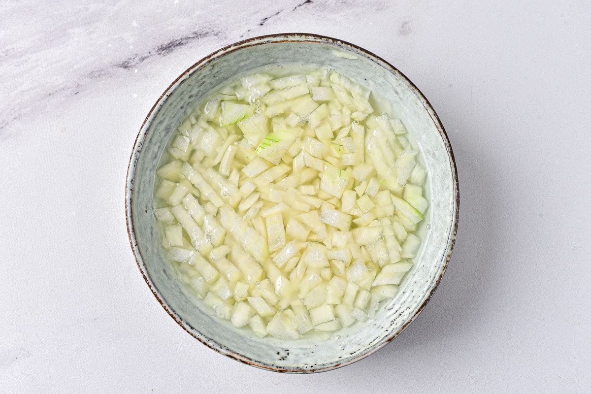 large bowl of onions sitting in apple cider vinegar on counter.