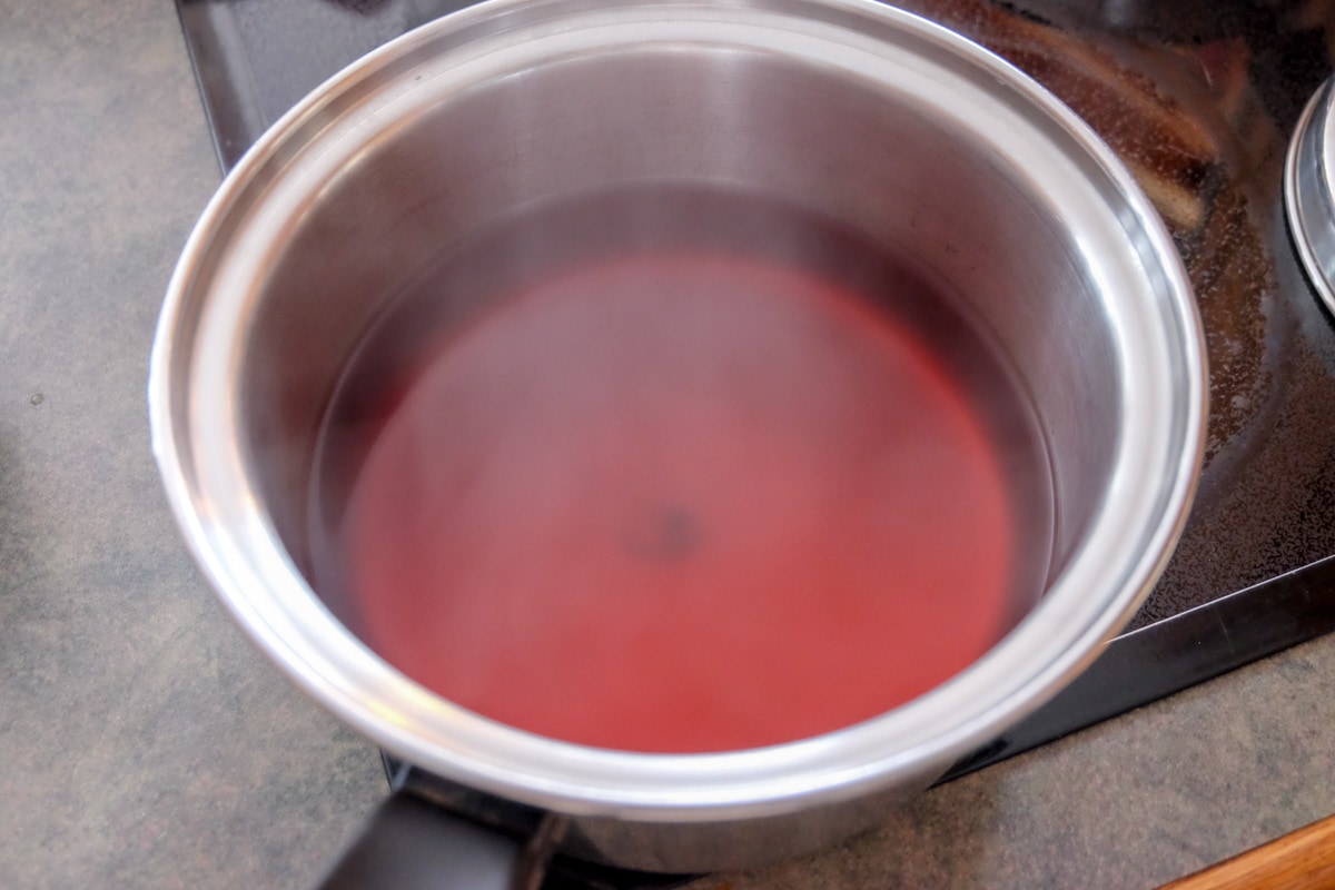 red fruity tea steeping in metal pot on stove.
