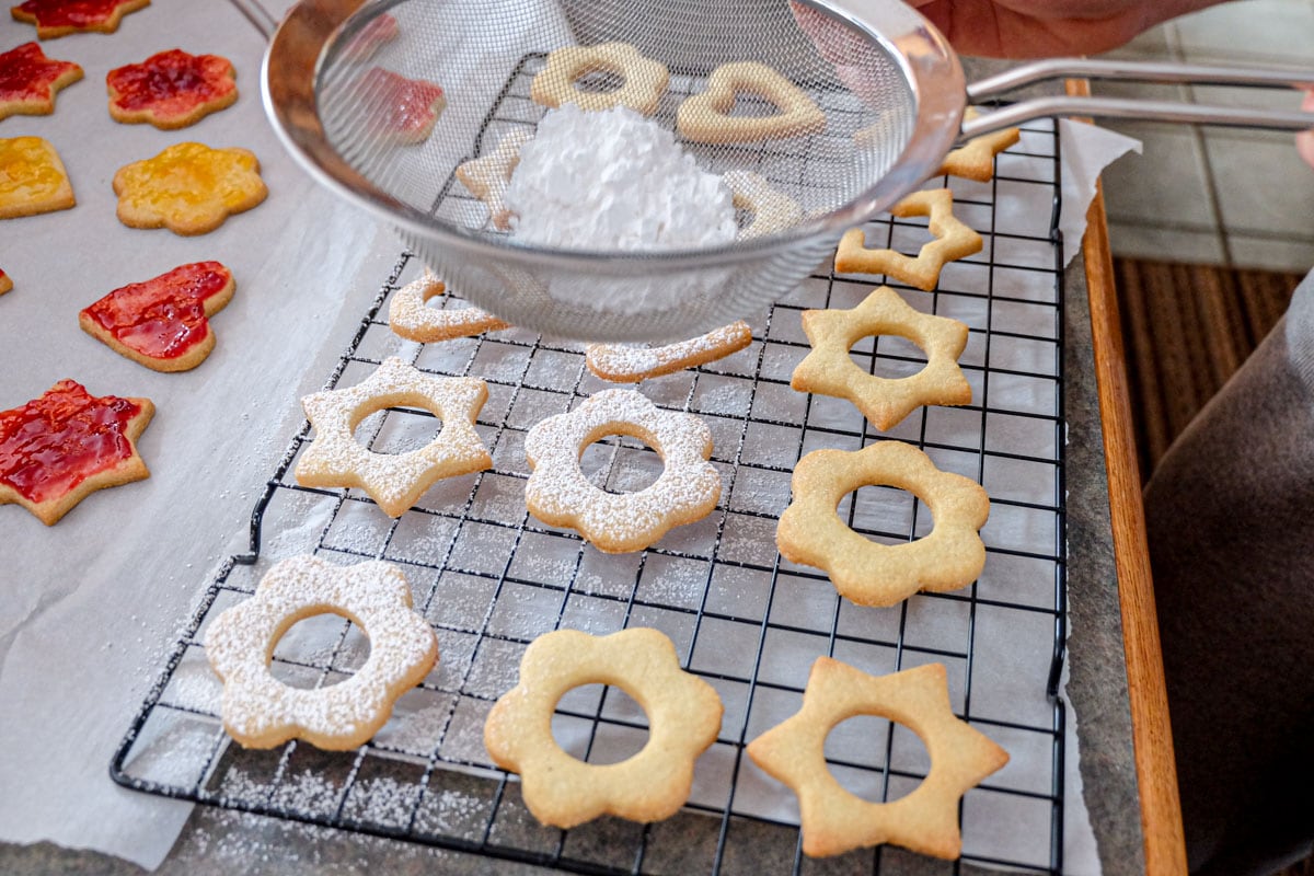 dusting powdered sugar through sifter onto baked cookie shapes on tray.