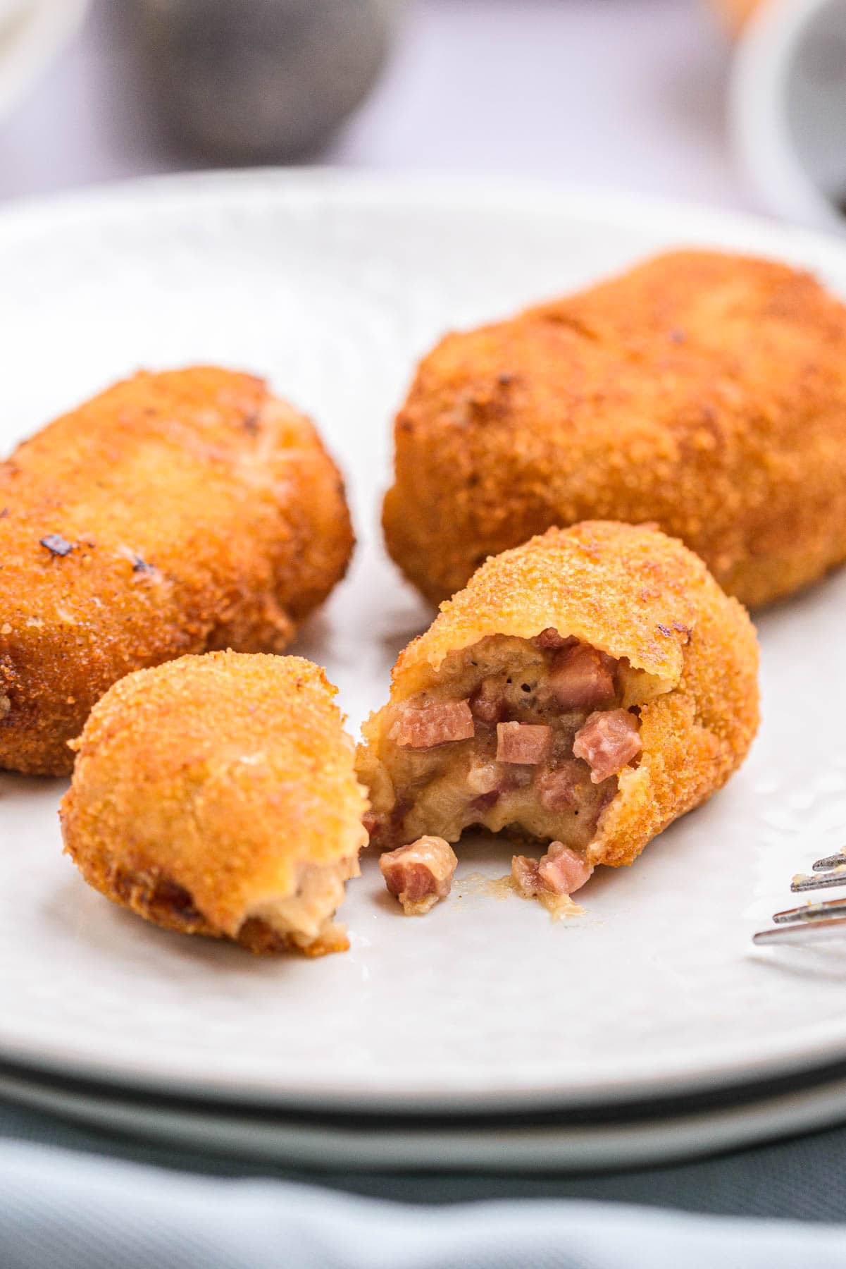 fried ham croquettes on plate one broken open to show ham filling.