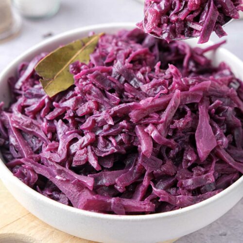 white bowl of german red cabbage with spoon lifting some out.