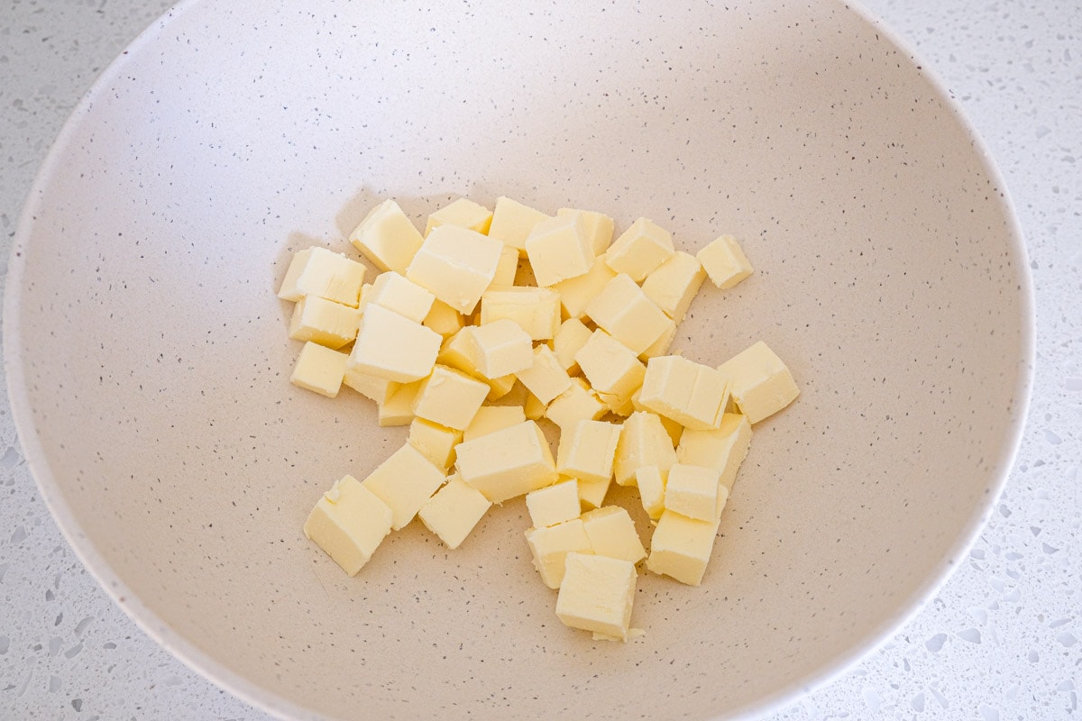 cubes of butter cut in white mixing bowl on counter.
