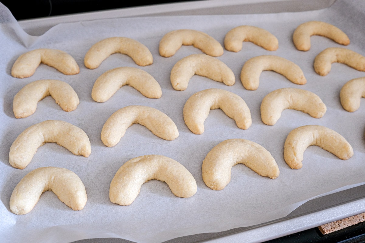 baked crescent cookies in parchment paper on cookie sheet.