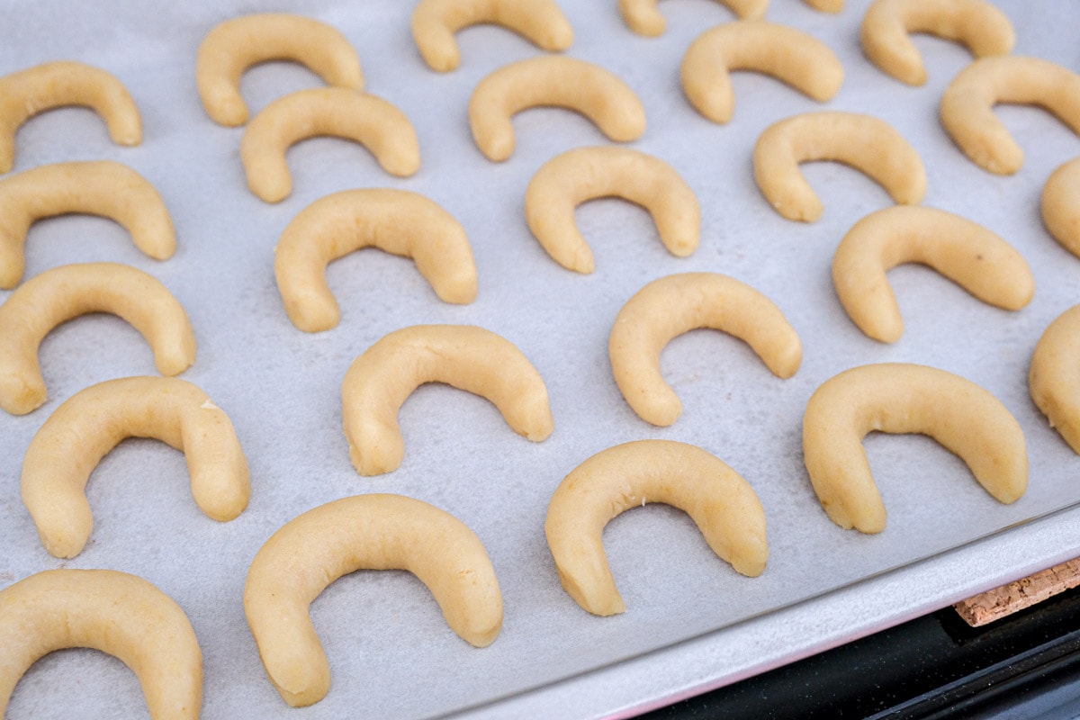 raw crescent cookies on parchment paper on cookie sheet.