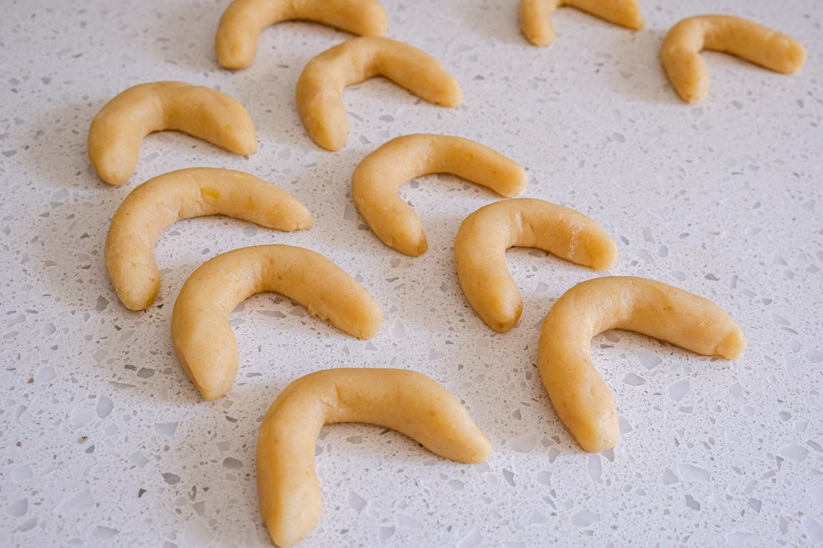 raw crescent cookies in a row on white counter top.