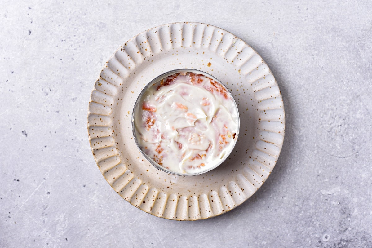 layers of grated carrots and mayo in round metal form sitting on small plate.