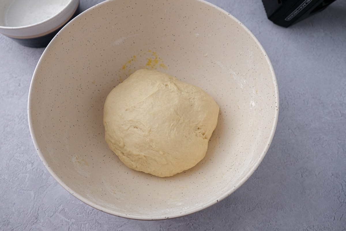 ball of dough in white mixing bowl on counter.