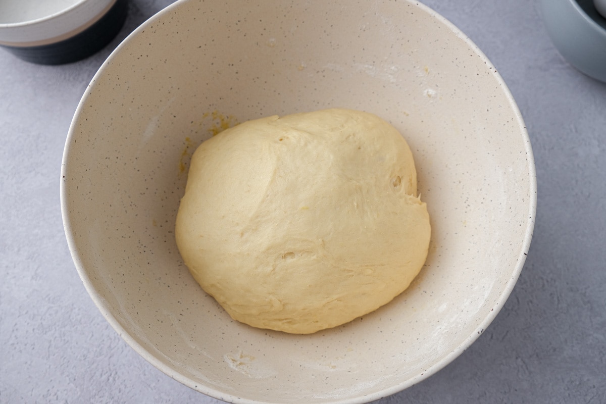 risen ball of yeast dough in white bowl on counter.
