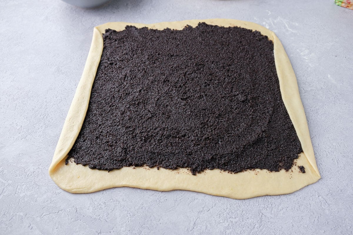 piece of rolled dough with poppy seed filling spread onto it with two edges folded over.