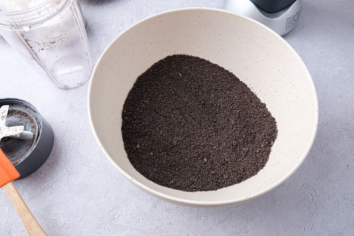 ground black poppy seeds in white mixing bowl on counter.