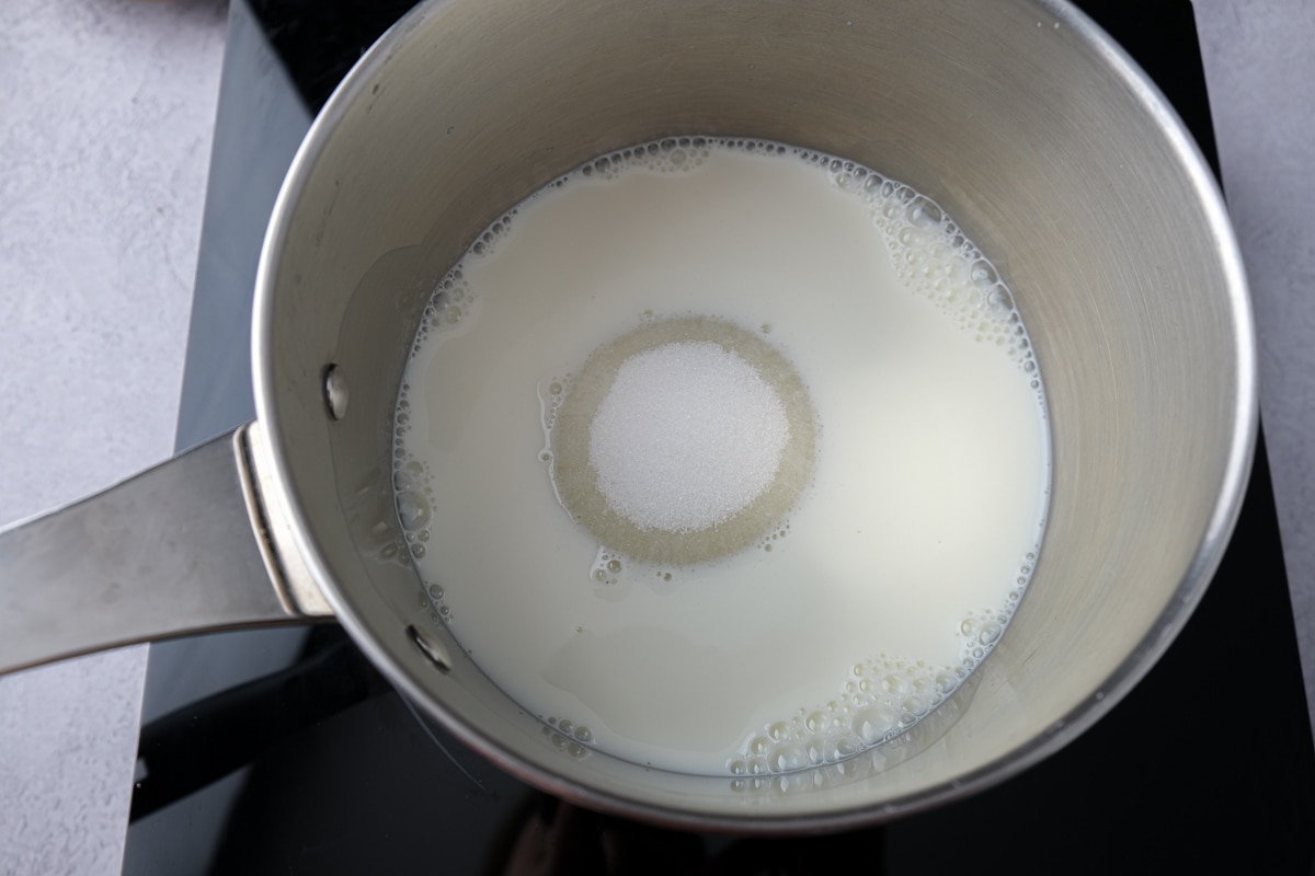 sugar and milk in silver pot on black hot plate.