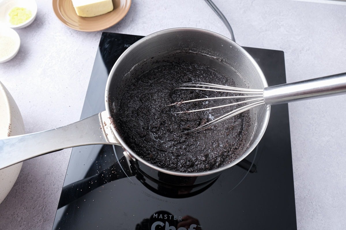 silver whisk mixing poppy seed filling in silver pot on hot plate.