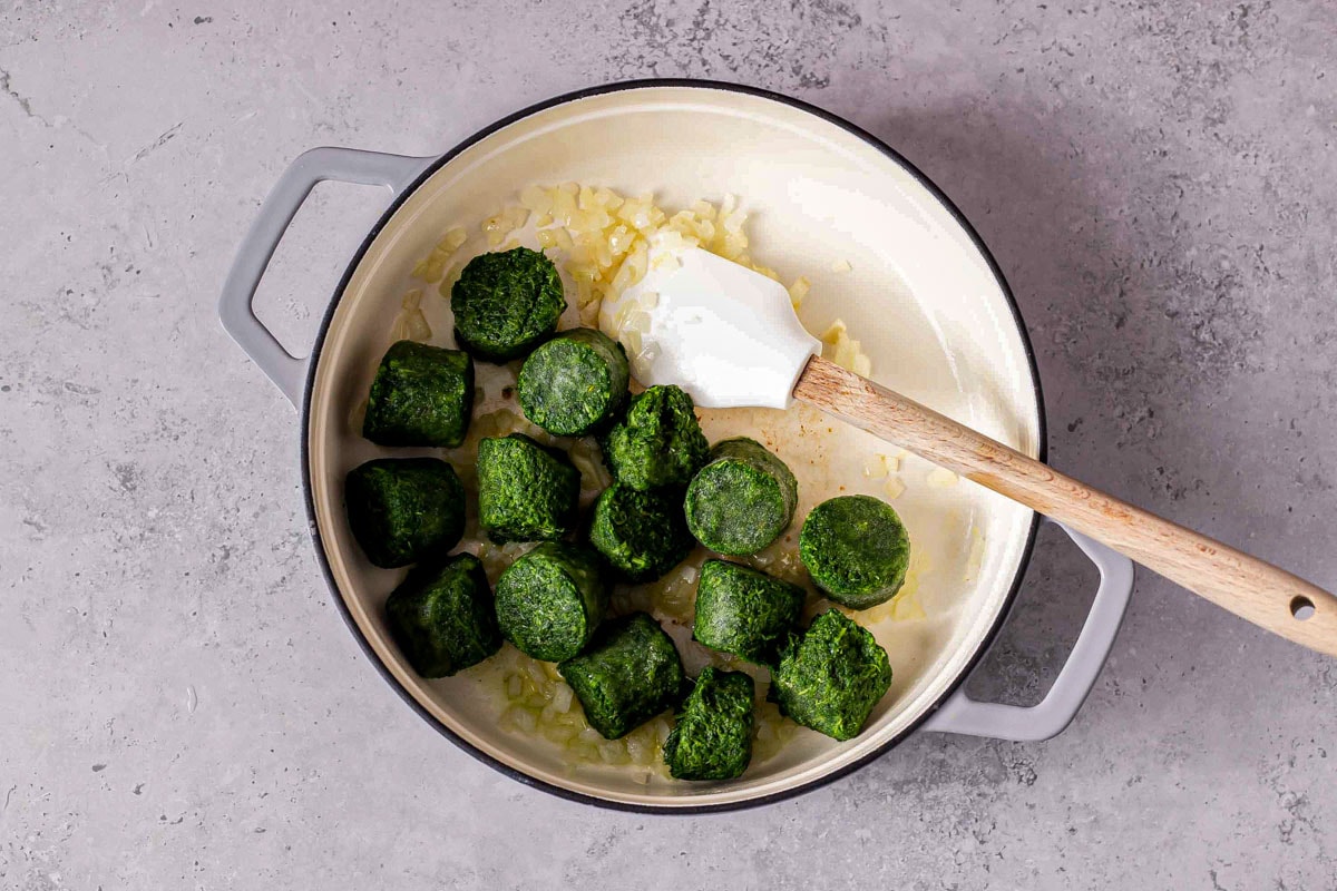 frozen spinach balls in large pot on counter with spatula sticking out.