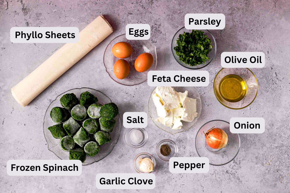 ingredients to make spanakopita on counter in bowls with labels.