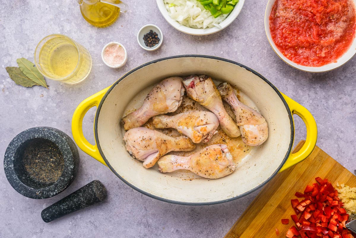 browned chicken drumsticks in large yellow pot sitting on counter top.