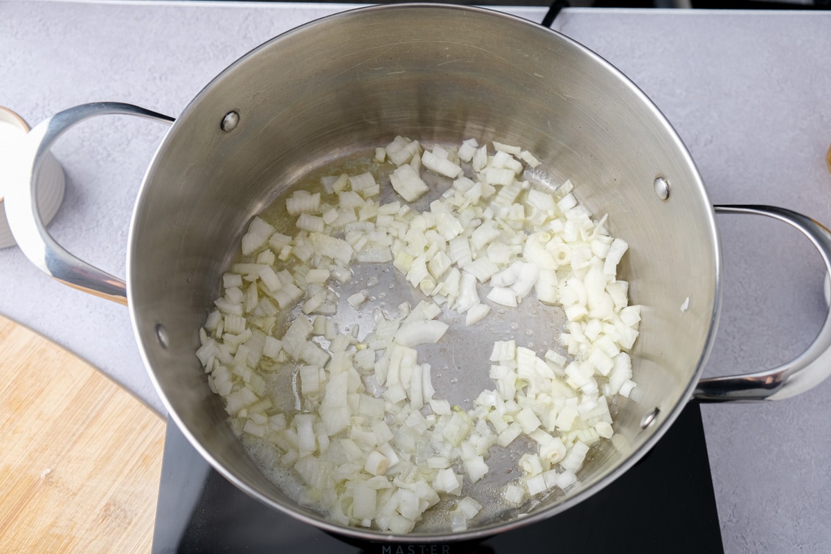 diced onions frying in large metal pot on hot plate.