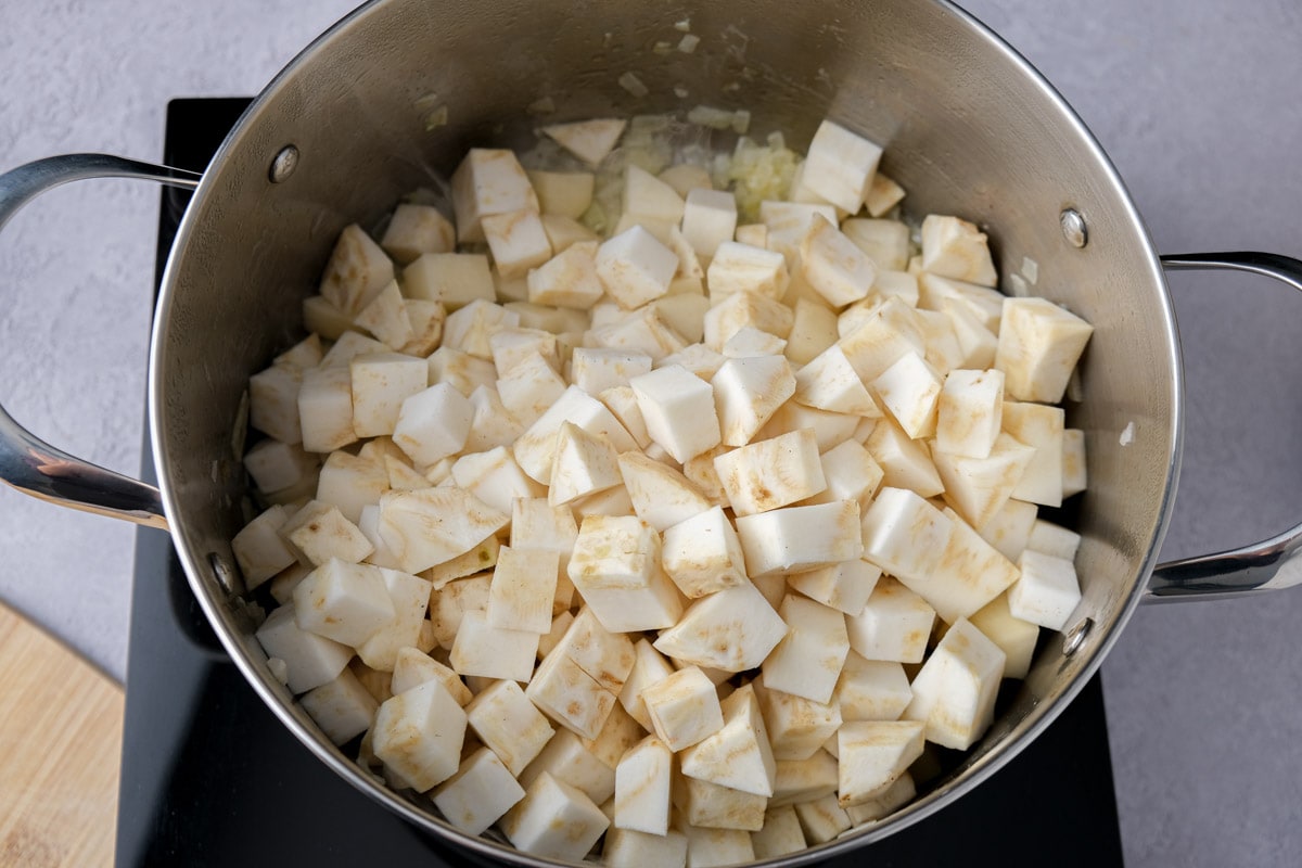 cubes of celeriac in large silver pot cooking on hot plate.