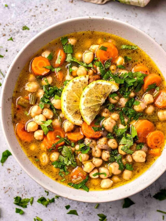 bowl of chickpea soup on counter with parsley around.