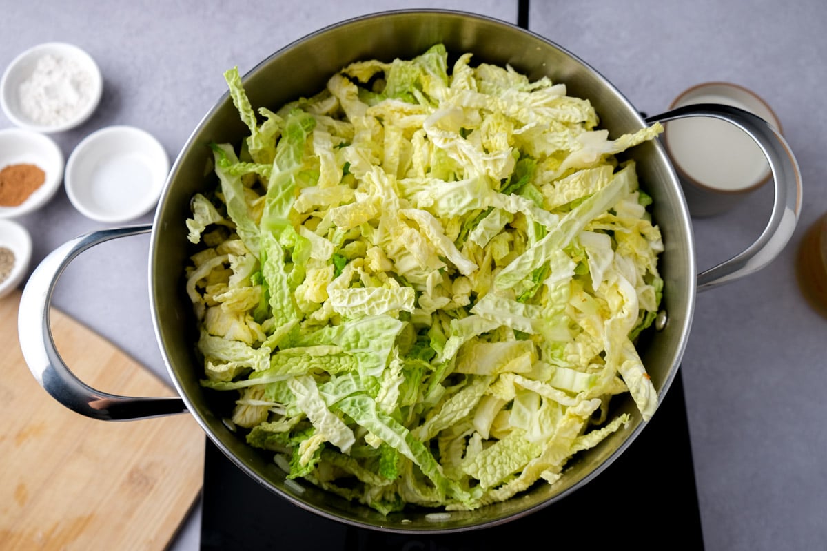 chopped savoy cabbage in large silver pot on counter top.