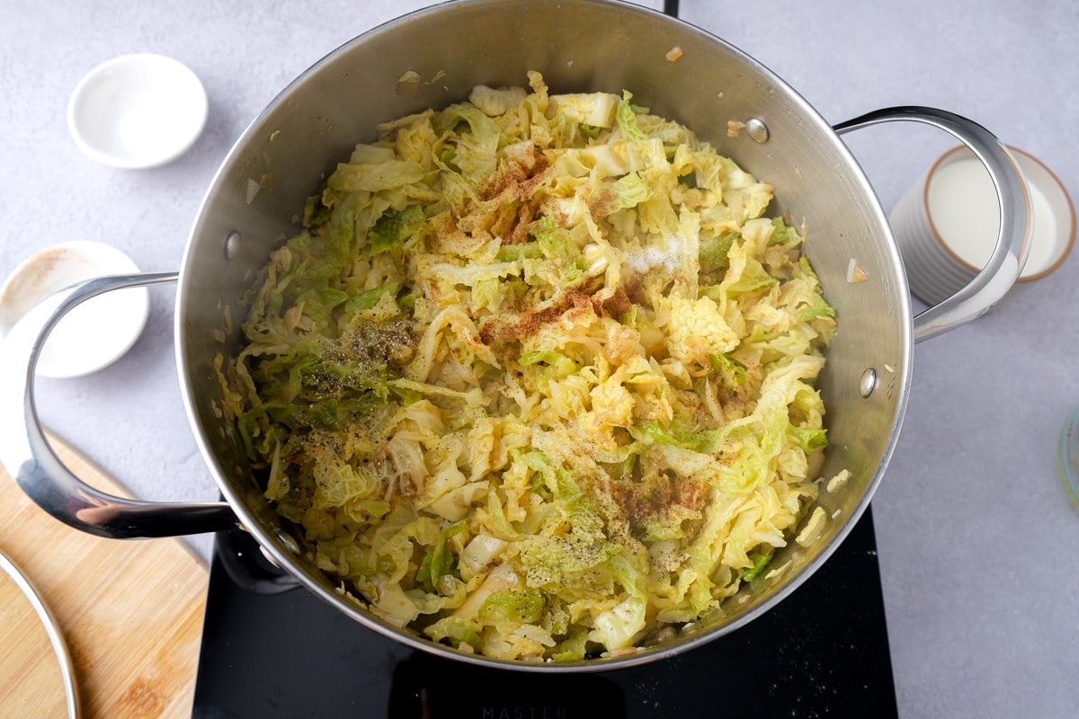 spices sprinkled on top of cooled savoy cabbage in large silver pot.