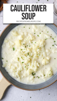 cauliflower soup with chunks on cauliflower in blue bowl with text overlay "cauliflower soup".
