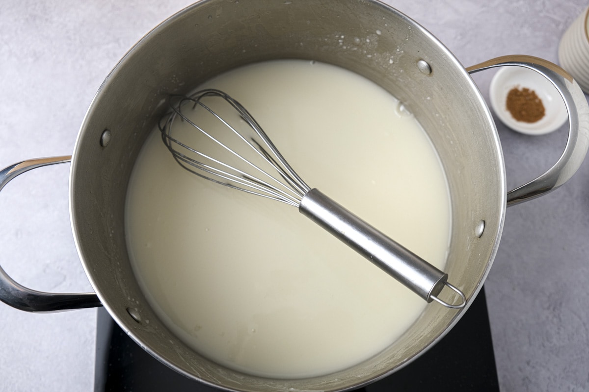 silver whisk in silver pot mixing cauliflower broth.