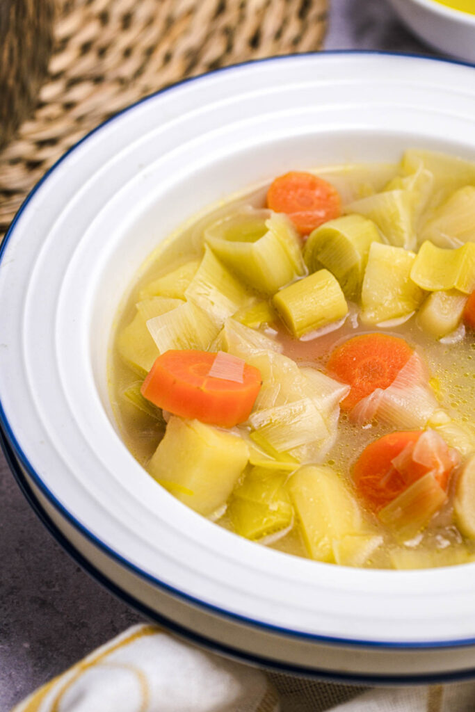 white bowl with large rim holding potato leek soup.